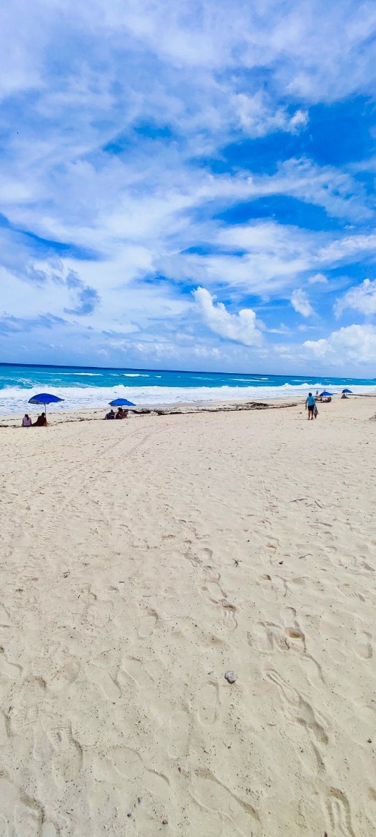 Playa San Miguelito en Cancún con sombrillas azules y cielo despejado. © 2024 Castor Daniel Oregel Maldonado